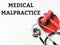 Phrase MEDICAL MALPRACTICE written on white background with gavel and stethoscope.