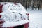 Phrase `Merry Christmas` written on snow covered car in winter forest.