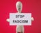 Phrase STOP FASCISM on the card of a wooden man on a red background
