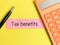 Phrase TAX BENEFITS written on strip paper with calculator and a pen isolated on yellow background.