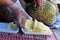 Phuket, Thailand food market: vendor cutting piece of fresh durian