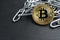 Physical Bitcoin gold coin on a convoluted shiny metal chain