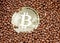 Physical golden bitcoin on a background of many gold granules