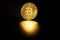 Physical shiny bitcoin agains dark background