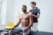 Physical therapist massaging a young black man on shoulder