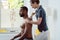 Physical therapist massaging a young black man on shoulder