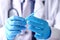 Physician arms wearing protective blue gloves prepare syringe