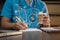 physician or practitioner in room writing on blank notebook and work on laptop computer, smartphone on the desk, Medic tech