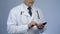 Physician typing message on cellphone, online consultation, modern technologies