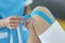 Physiotherapist apply kinesiology blue tape on client knee