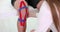 Physiotherapist applying kinesiotape to patient knee in clinic closeup