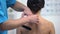 Physiotherapist applying Y-shaped tapes on female patient shoulder muscle strain