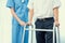 Physiotherapist assists her contented senior patient on folding walker.