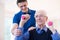 Physiotherapist Helping Senior Man To Lift Hand Weights