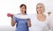 A physiotherapist helps an older woman recover from an injury through exercise with dumbbells.