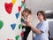 physiotherapist instructor helping little girl to climb wall in gym. sensory integration for kid and correctional