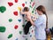 physiotherapist instructor helping little girl to climb wall in gym. sensory integration for kid and correctional