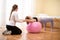 Physiotherapist working with young female client on core strength using fitball. Rehabilitation and physiotherapy background.