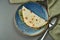 Piadina - classic Italian tortilla-bread with Vitello tonato veal, arugula, mozzarella and tomatoes on a blue plate on wooden