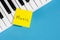 Piano keys and paper reminder with word Music on a blue background.