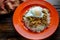 Picadillo a Cuban dish made of ground beef served on a bed of rice with a sunny side up egg on a red plate on a wooden kitchen tab