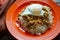 Picadillo a Cuban dish made of ground beef served on a bed of rice with a sunny side up egg on a red plate on a wooden kitchen tab