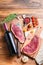 Picanha organic beef steaks over old american butcher cleaver with seasonings and red wine bottle on wooden table. Top view