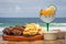 Picanha, a traditional cut of Brazilian meat, served with fried cassava on a hot plate. In the background there`s a tropical drin