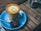 Piccolo Latte coffee topping with flower art from milk in small glass with a piece of homemade brownies cake on blue ceramic plate