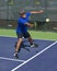 Pickleball Action - Man Wearing Blue Gritting Teeth While Stretching To Hit Forehand Shot