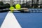 Pickleball paddles and two yellow whiffle balls on a blue court on white line