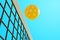 A pickleball sports ball flies over the net.