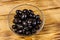 Pickled black olives in glass bowl on wooden table
