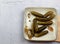 Pickled cucumbers on a light rectangular plate on a wooden cutting board on a light gray background.