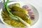 Pickled cucumbers on a white plate next to the onion rings and green onion arrow. homemade vegetables for a healthy diet.