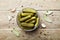 Pickled gherkins or cucumbers in bowl on wooden rustic table from above.