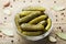 Pickled gherkins or cucumbers in bowl on wooden vintage table.