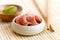 Pickled pink ginger slices in wooden bowl on bamboo mat next to