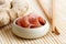 Pickled pink ginger slices in wooden bowl on bamboo mat next to