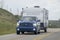 A pickup truck towing a camper RV trailer during summer time on the route