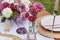 Picnic aesthetics table setting, flowers arrangement, shells. Cozy setup with flowers and candles