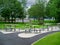 Picnic area by office building for staff breaks outdoors. Modern metal table and seat. Green trees and green grass