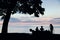 Picnic on the beach. Three silhouettes of people and a tree. Blurred photo for background