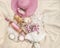 Picnic on beige blanket: pink sun hat, rose wine bottle with empty label, wine glass, baguette, cheese, candles and pink flowers