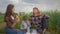 Picnic, cheerful female feeds buns man buns while relaxing with kid boy milk drinker at family picnic outdoors in green