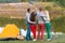 Picnic with friends in at lake near camping tent. Company friends having hike picnic nature background. Hikers relaxing during