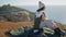 Picnic girl pouring coffee on cliff edge alone. Carefree tourist resting ocean