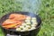 Picnic outdoors in the summer. Cooking on a round grill fish sea bass and zucchini slices