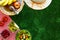 Picnic in summer with products, sandwich, salad, fruits, drink and hat on green grass texture background top view mockup