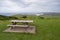 Picnic table with benches on green lawn with views of coastline